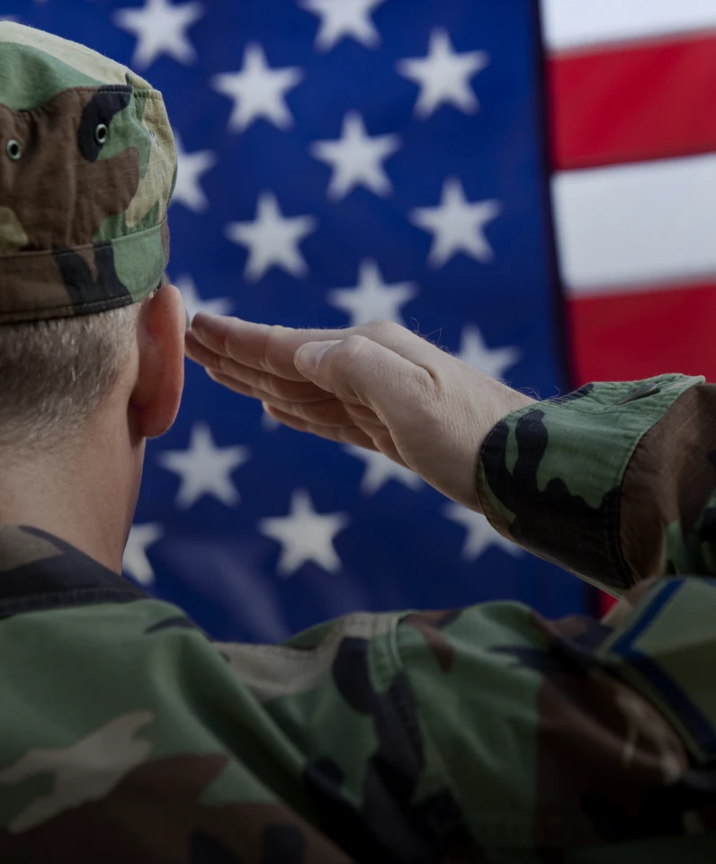 Uniformed soldier saluting American flag