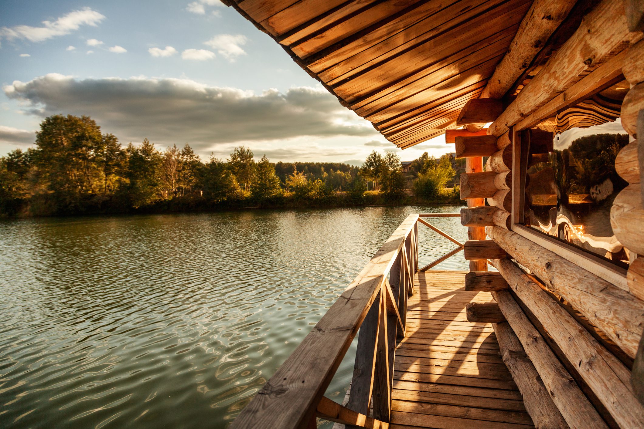 Log cabin deck overlooking peaceful lake at sunset