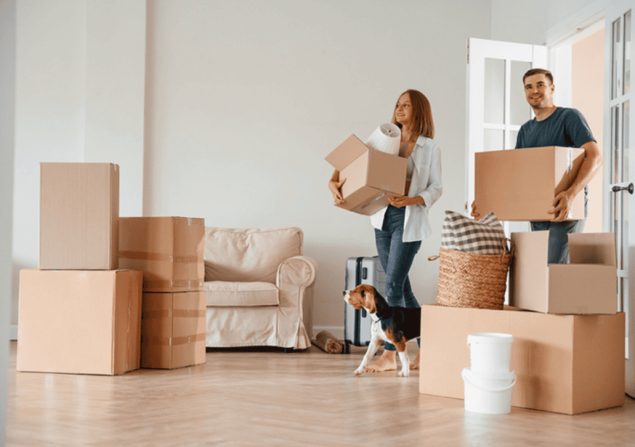 Couple carrying moving boxes with dog